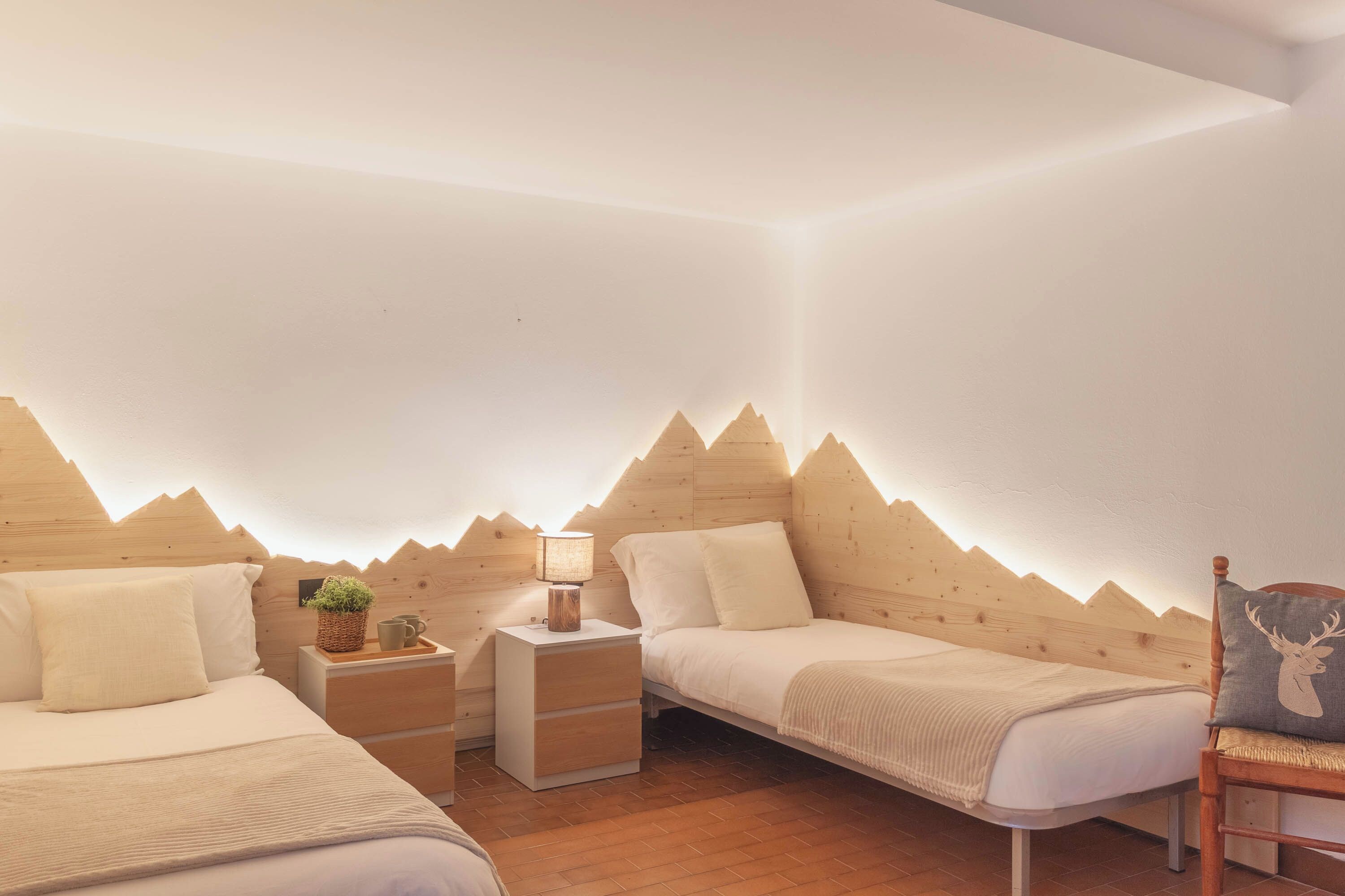A bedroom with two beds, a nightstand, a lamp, and a chair.