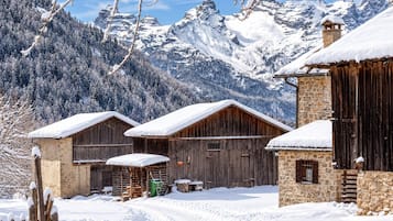Un village de montagne enneigé, avec des bâtiments en bois et une structure en pierre.