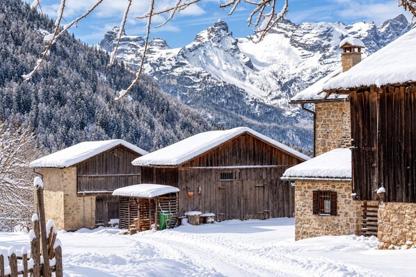 A snow-covered mountain village with wooden buildings and a stone structure.