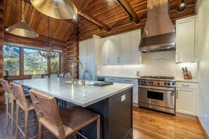 A kitchen with a large island, wooden cabinets, and a view of mountains. - Newly Furnished 3BR Ski Townhome Sleeps 8 + Private Hot Tub (Mountain Village)