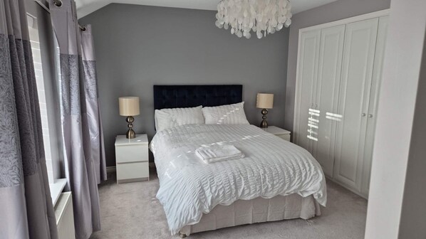 A bedroom with a bed, two bedside tables, a chandelier, and a wardrobe. - Wrexham Retreat Villa, 4 bedrooms, 4 beds, 3 Baths (Brymbo)