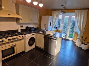 A compact kitchen with a stove, washing machine, and dishwasher. - Wrexham Retreat Villa, 4 bedrooms, 4 beds, 3 Baths (Brymbo)