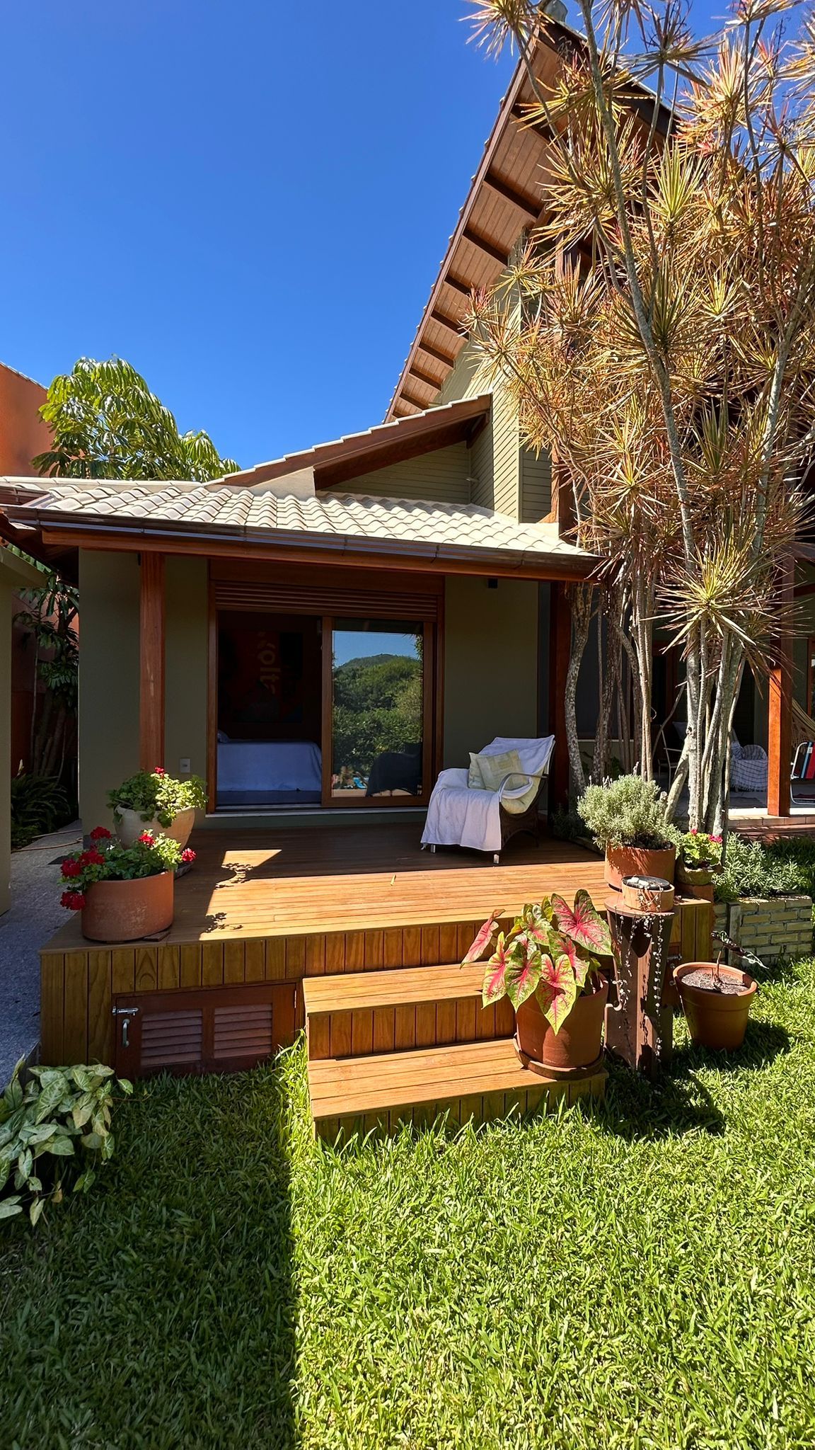 A house with a covered porch, a chair, and potted plants.