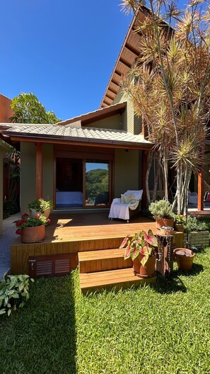 Una casa con porche cubierto, una silla y plantas en macetas.