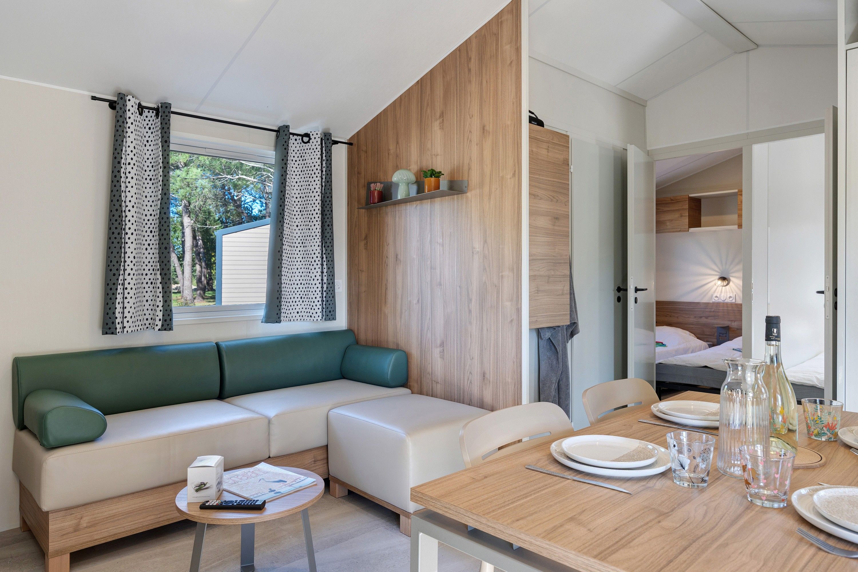 Een moderne woonkamer met een bank, een eettafel en een bed op de achtergrond.