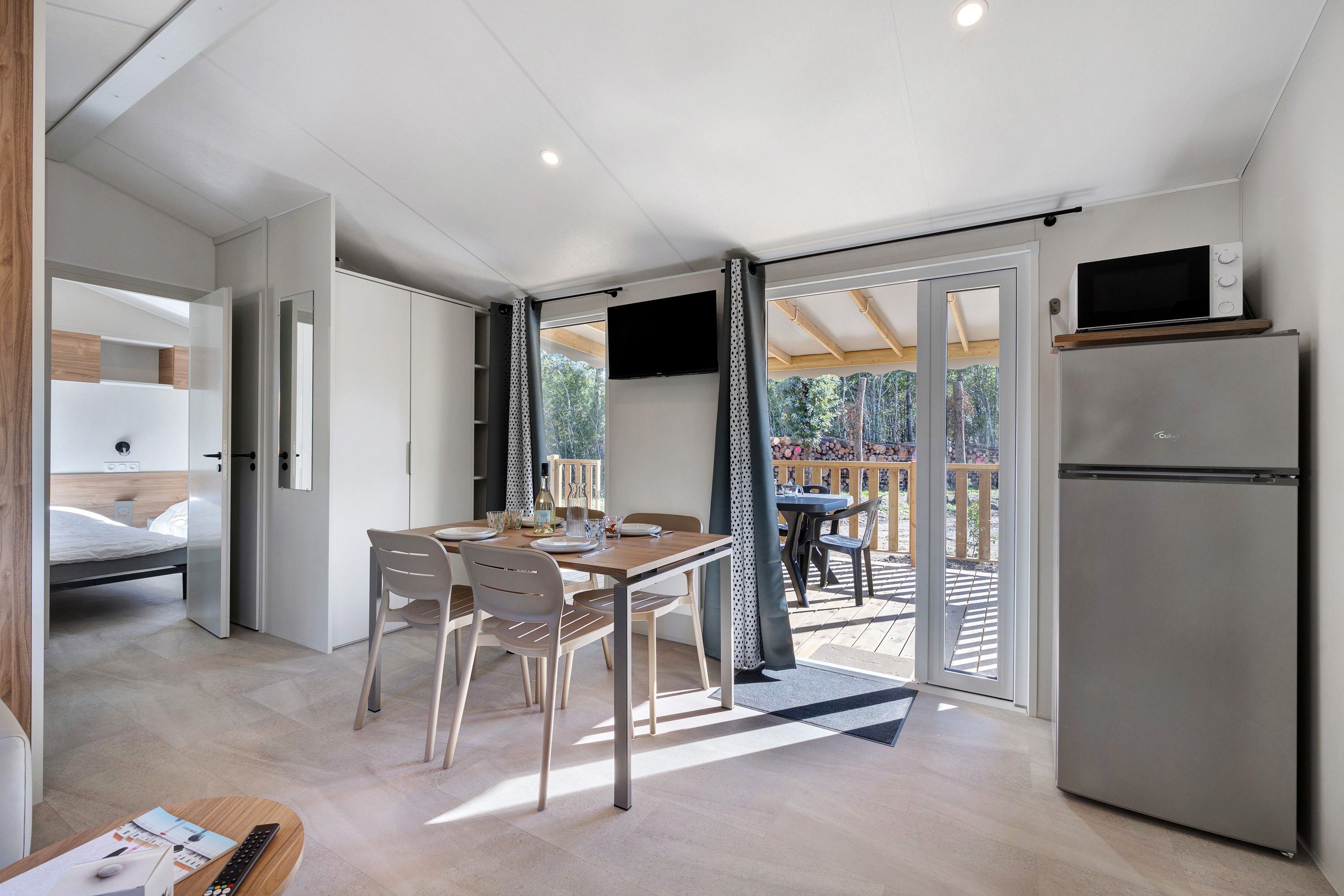 Eine moderne Küche mit integriertem Kühlschrank, ein Essbereich mit Tisch und Stühlen sowie ein Blick auf die Außenterrasse.