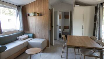 Ein modernes Interieur mit einer Couch, einem runden Tisch, einem Esstisch mit Stühlen und einem Kleiderschrank.