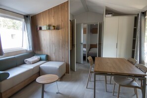 En modern inredning med en soffa, ett runt bord, ett matbord med stolar och en garderob.