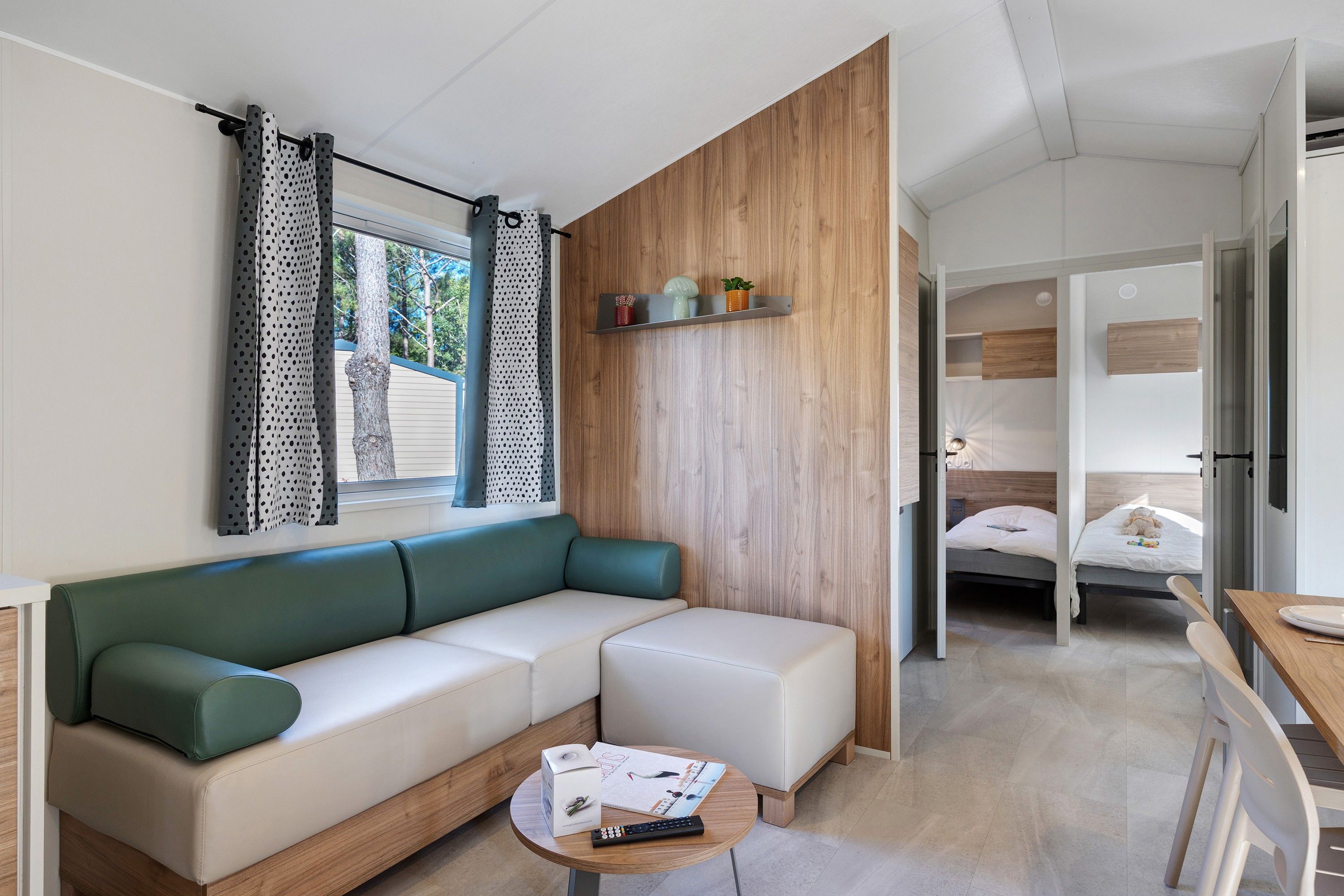 Ein moderner, kompakter Wohnraum mit einer Couch, einem kleinen Tisch mit Fernbedienung und einer Wand als Holzoptik.