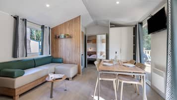 Ein stilvolles Wohnzimmer mit Sofa, Esstisch und Fernseher.