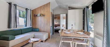 A modern living space with a sofa, a dining table, and a TV.
