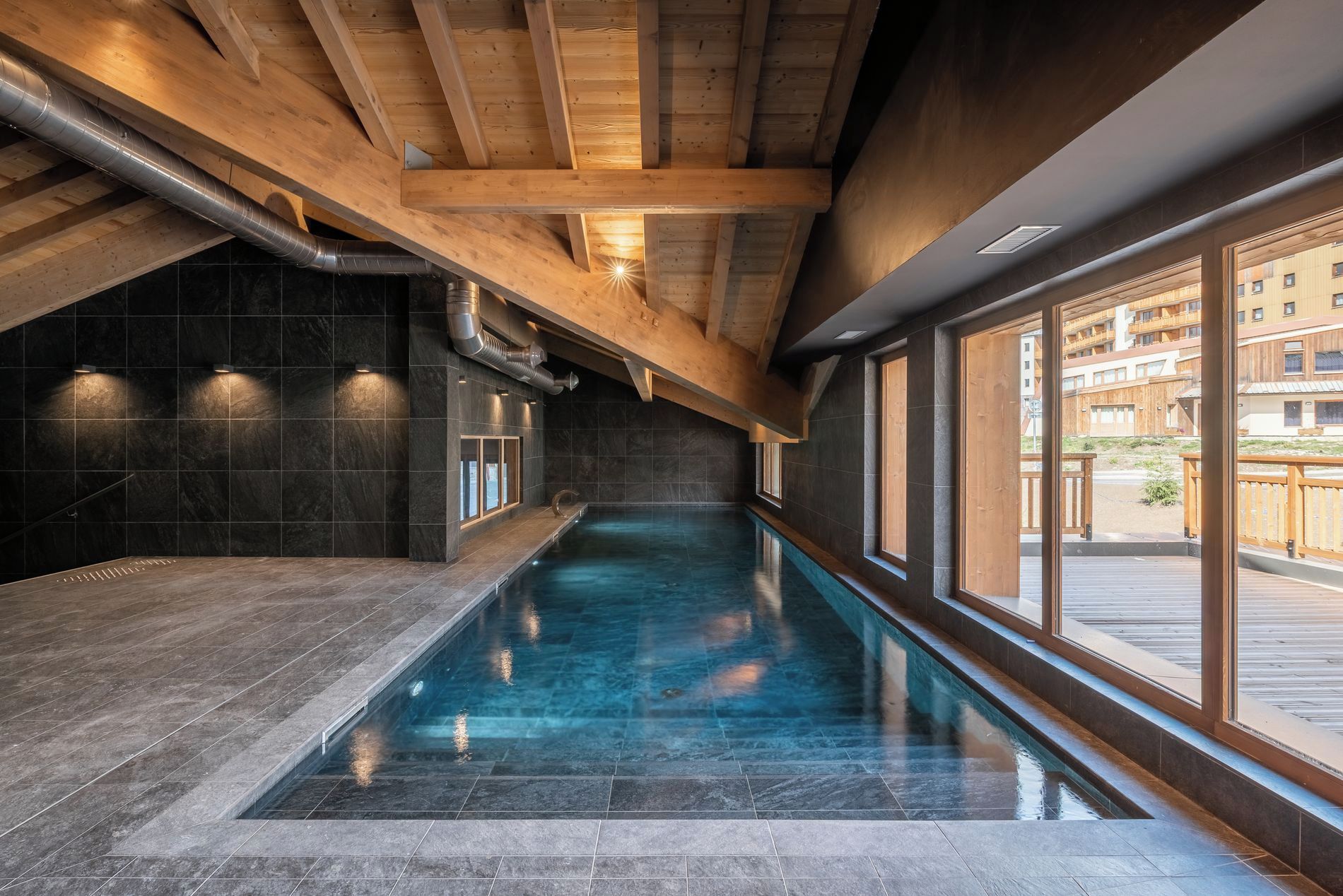 An indoor swimming pool with a view of the outside.