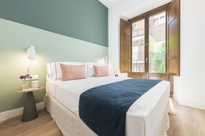 A bedroom with a bed, bedside tables, a lamp, and a window with a view of a building. - Santa Ana XXXI / XLV TUR (Madrid)