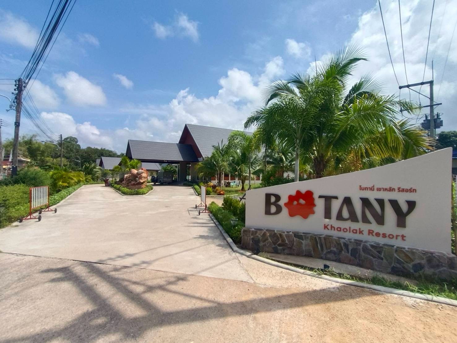 A sign for Botany Khaolak Resort with a clear entrance and a paved driveway.