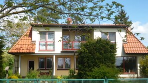 A two-story house with a red-tiled roof, multiple windows, and a balcony. - Apartment 'Petronela' with Lake View, Private Terrace and Wi-Fi (Waren (Müritz))