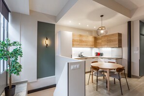 A modern kitchen with wooden cabinets, a dining table, and chairs. - Spacious 3-Bedroom Apartment in a Lively Parisian Neighborhood (Paris)