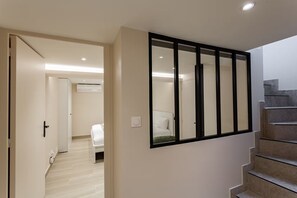 A modern interior with a staircase, a hallway, and a room with a bed. - Spacious 3-Bedroom Apartment in a Lively Parisian Neighborhood (Paris)