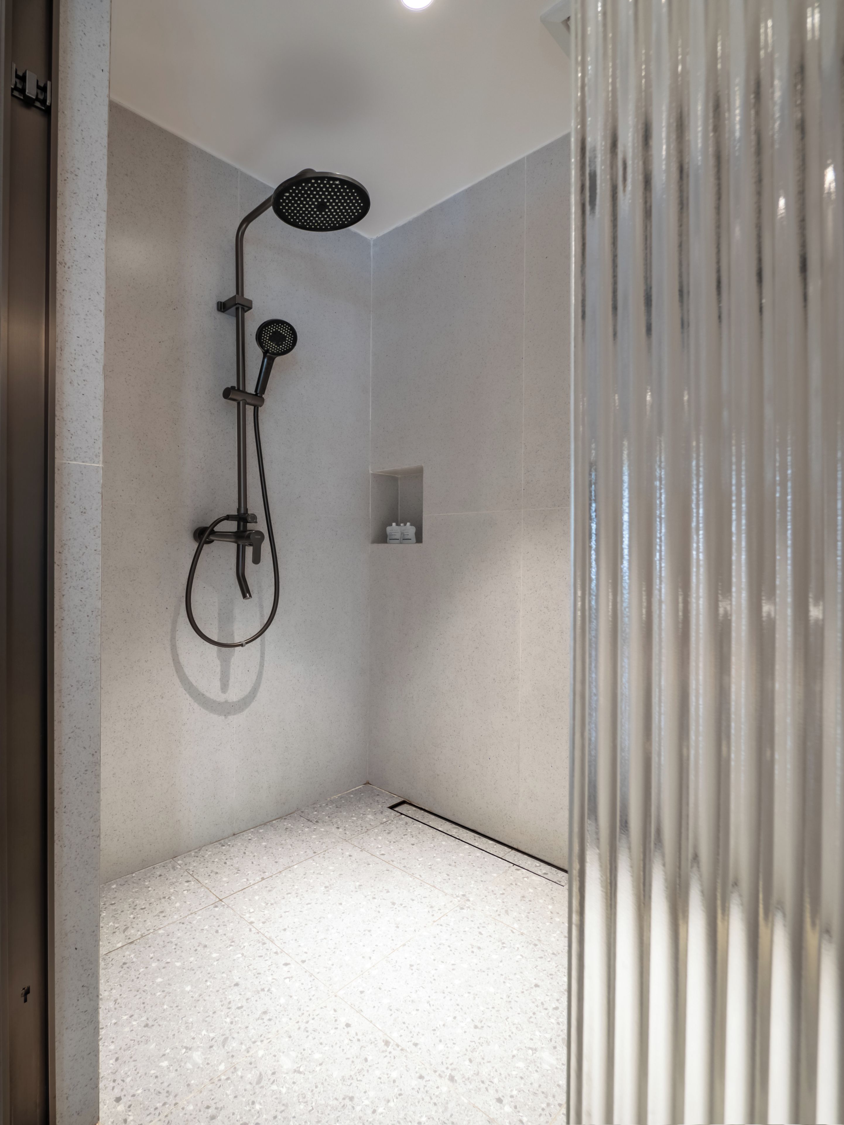 A modern shower with a handheld showerhead and a wall-mounted rain showerhead.