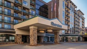 Un hotel Sheraton con fachada de piedra, varios balcones y cielo despejado.