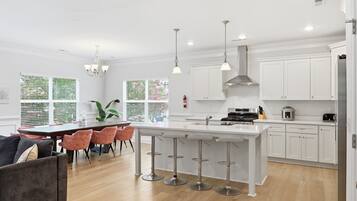 A modern kitchen with white cabinets, a central island with bar stools, and pendant lighting.