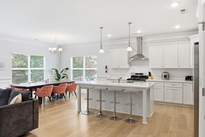 A modern kitchen with white cabinets, a central island with bar stools, and pendant lighting. - Fabulous 4-bedroom house in tranquil Norfolk with Game Room! (Norfolk)