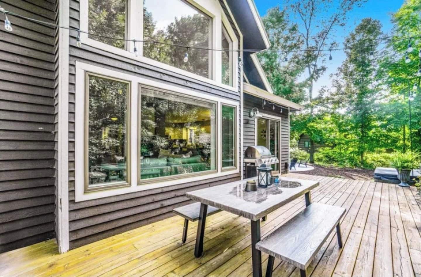Ein modernes Haus mit Terrasse, großen Fenstern und Gartenmöbeln.