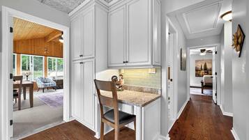 Une cuisine avec des meubles blancs, un plan de travail en granit et une chaise en bois.