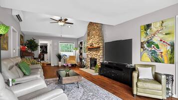 A spacious living room with a fireplace, a television, and a large painting.