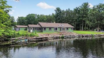 A lakeside property with a main house and a smaller structure, surrounded by trees and a dock.