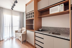A modern kitchen with a built-in microwave, a stainless steel sink, and wooden cabinetry. - Becker by Bhomy (São Paulo)