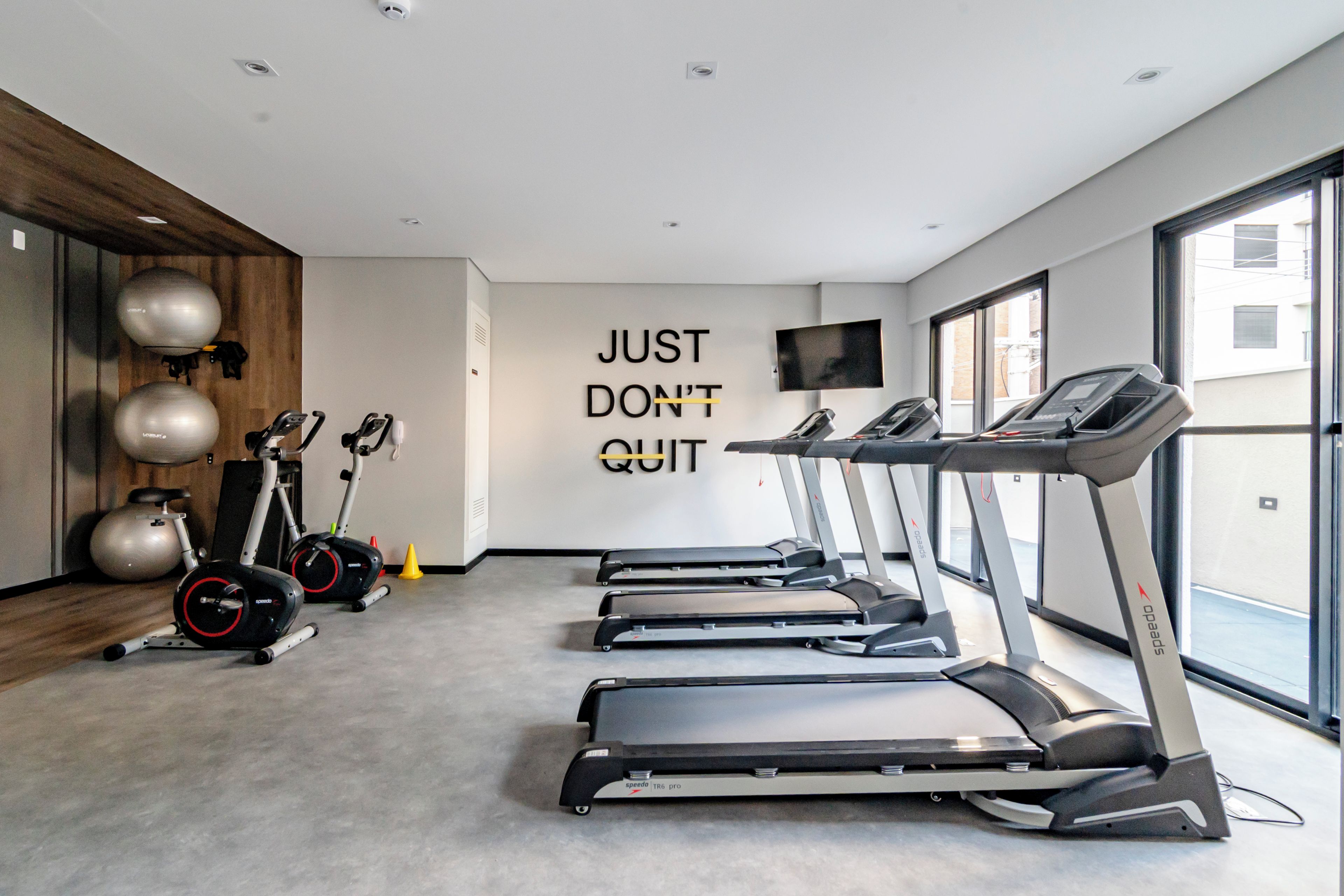 A gym with treadmills, stationary bikes, and exercise balls.