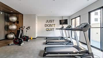 A gym with treadmills, stationary bikes, and exercise balls.