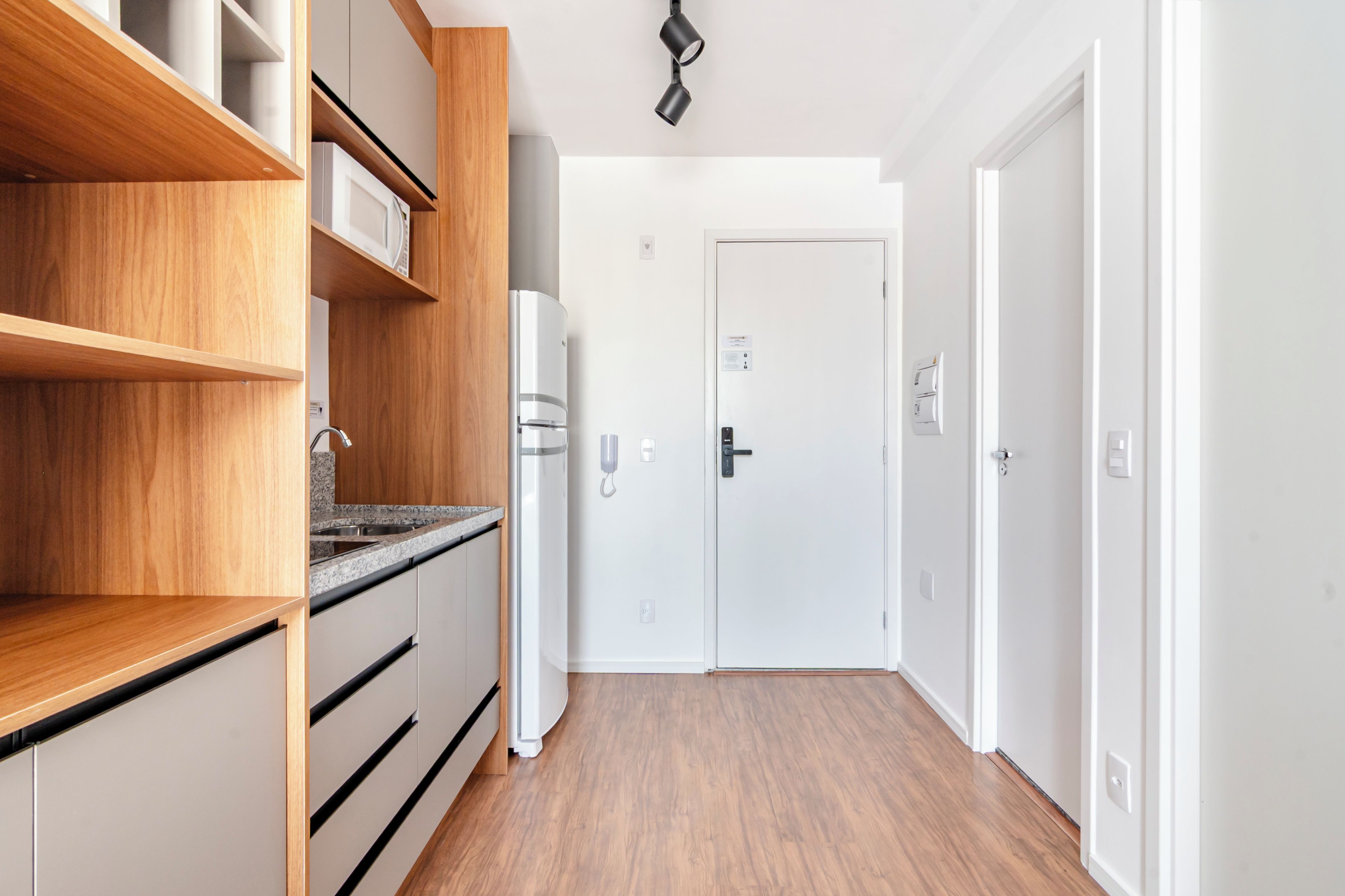 A modern kitchen with wooden cabinets, a built-in oven, and a stainless steel sink.
