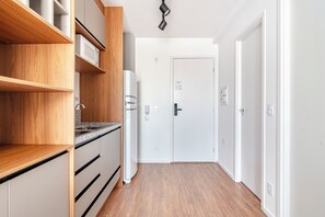 A modern kitchen with wooden cabinets, a built-in oven, and a stainless steel sink. - Becker by Bhomy (São Paulo)