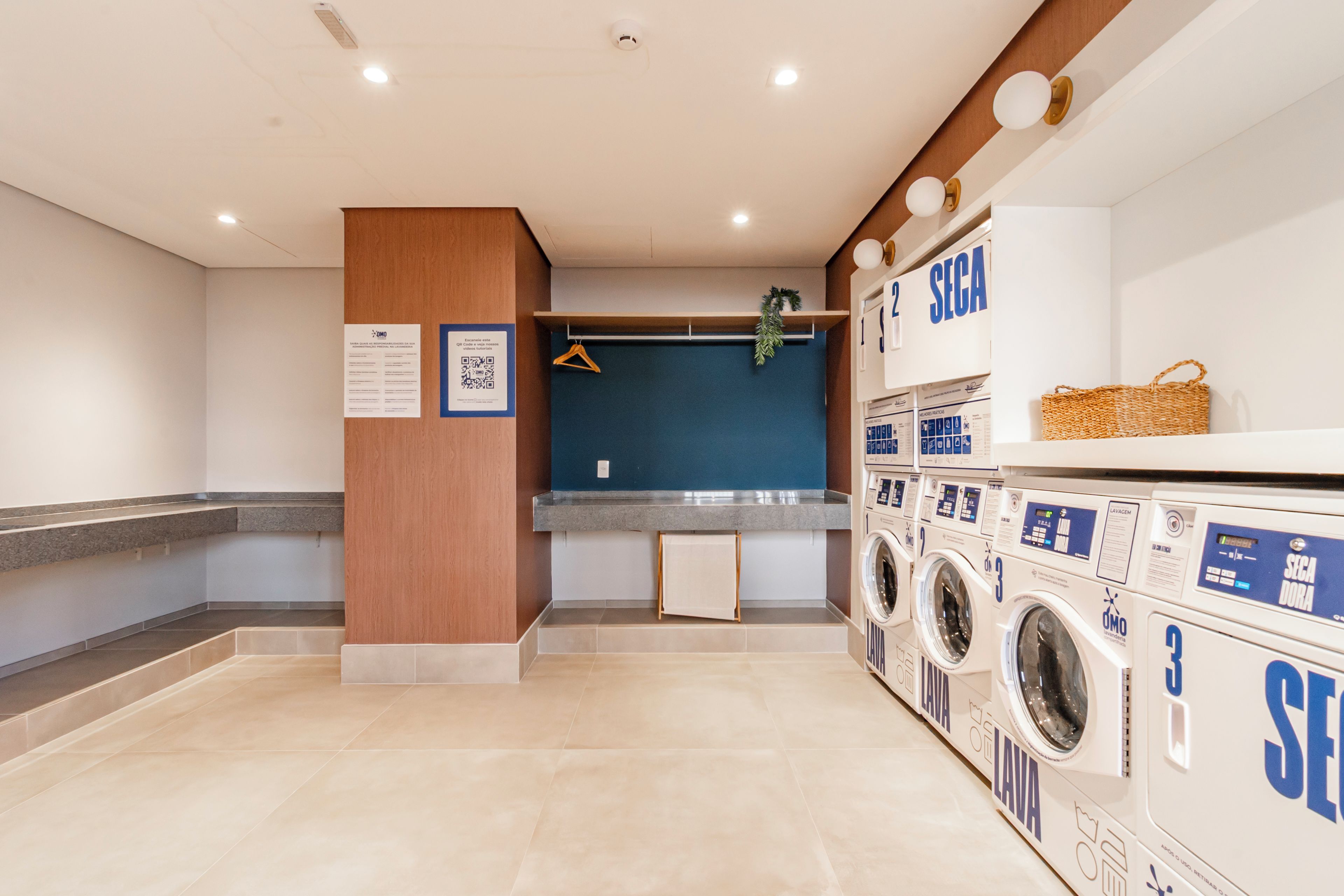 A laundry area with multiple washing machines, a blue wall, and a wooden column.