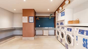 A laundry area with multiple washing machines, a blue wall, and a wooden column.