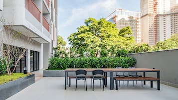 A modern outdoor seating area with a table and chairs, surrounded by greenery and a view of a construction site.