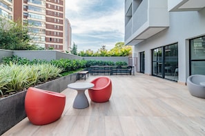 An outdoor patio area with seating arrangements, a table, and a view of surrounding buildings. - Becker by Bhomy (São Paulo)