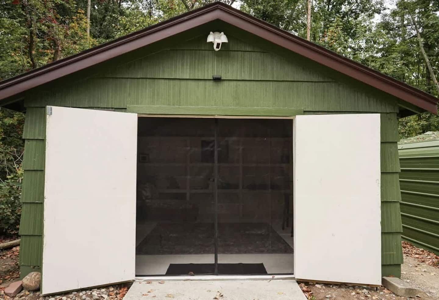 A green shed with a large open door and a small window at the top.
