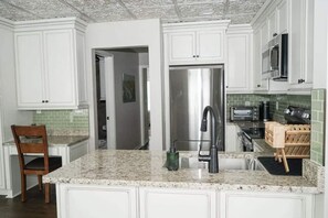 A kitchen with white cabinetry, a stainless steel refrigerator, a built-in oven, and a microwave.
