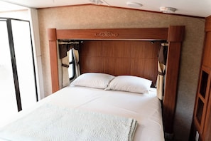 A bed with a wooden headboard, white bedding, and a window with curtains.