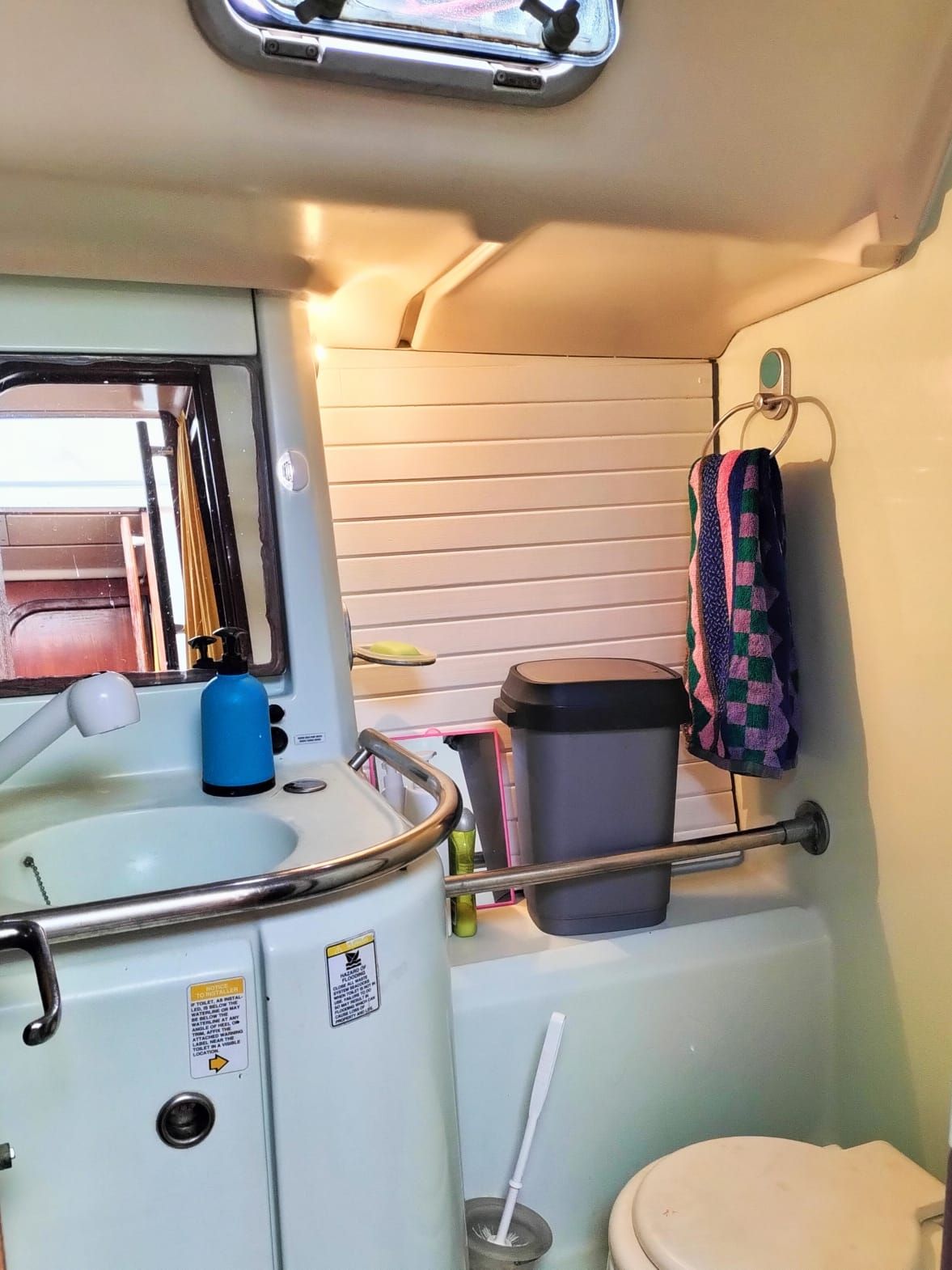 Ein kleines Badezimmer mit Waschbecken, Toilette und einem Fenster über dem Waschbecken.