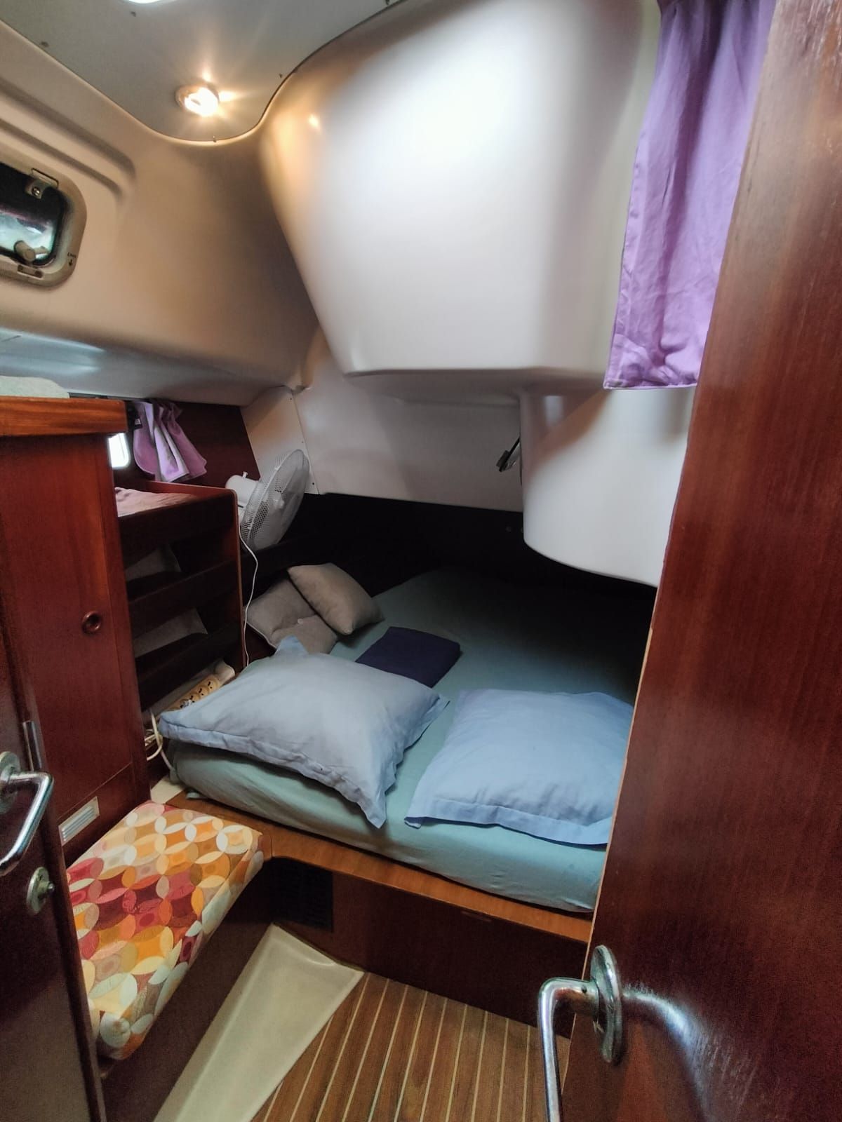 Eine gemütliche Kabine mit Etagenbett, einer kleinen Sitzecke und einem Holzschrank.