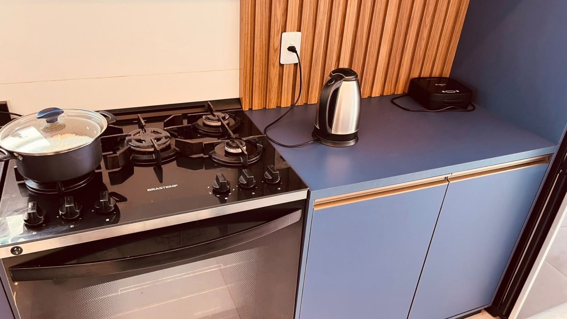 Una cucina con un fornello, una pentola sulla fiamma, un bollitore e una macchina per il caffè.