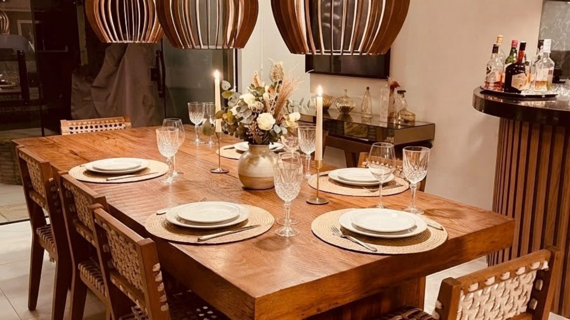 A dining table set with plates, cutlery, and wine glasses, surrounded by chairs.