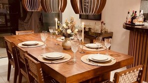 A dining table set with plates, cutlery, and wine glasses, surrounded by chairs. - Vrbo Property (São Pedro da Aldeia)