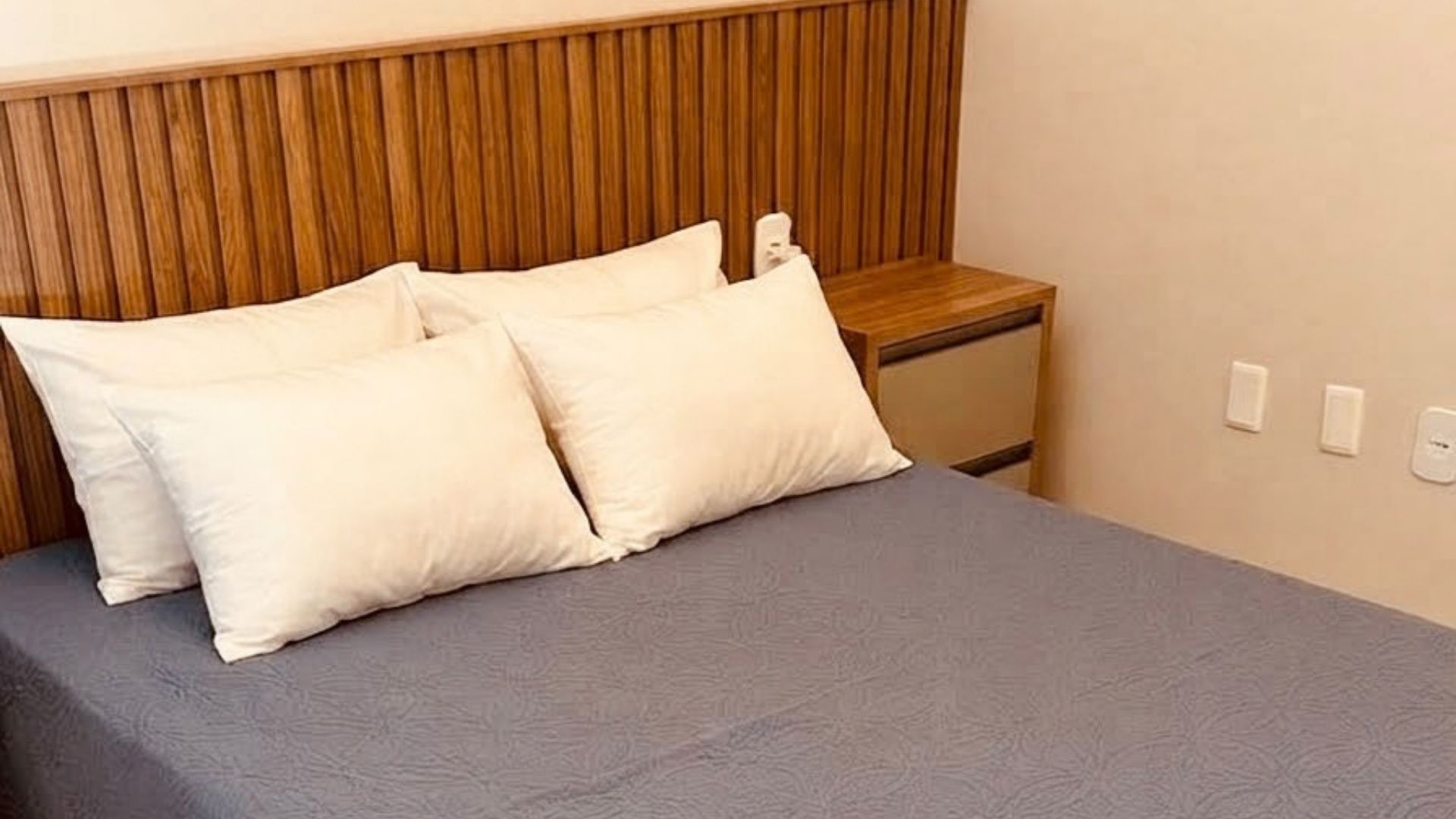 A bed with two pillows and a wooden headboard.