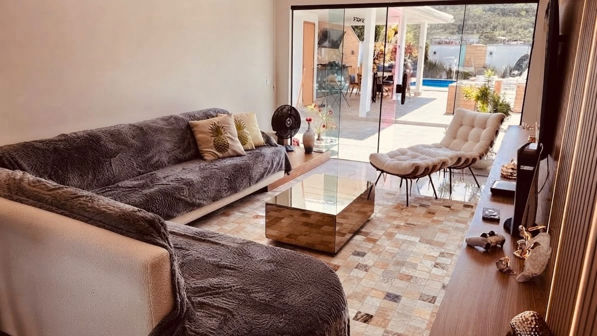 Una sala moderna con un sofá, una mesa de centro de vidrio y un sillón.