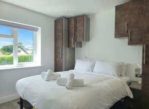 Habitació d'hotel amb un llit gran, una finestra que dona a zones verdes i armaris de fusta integrats.