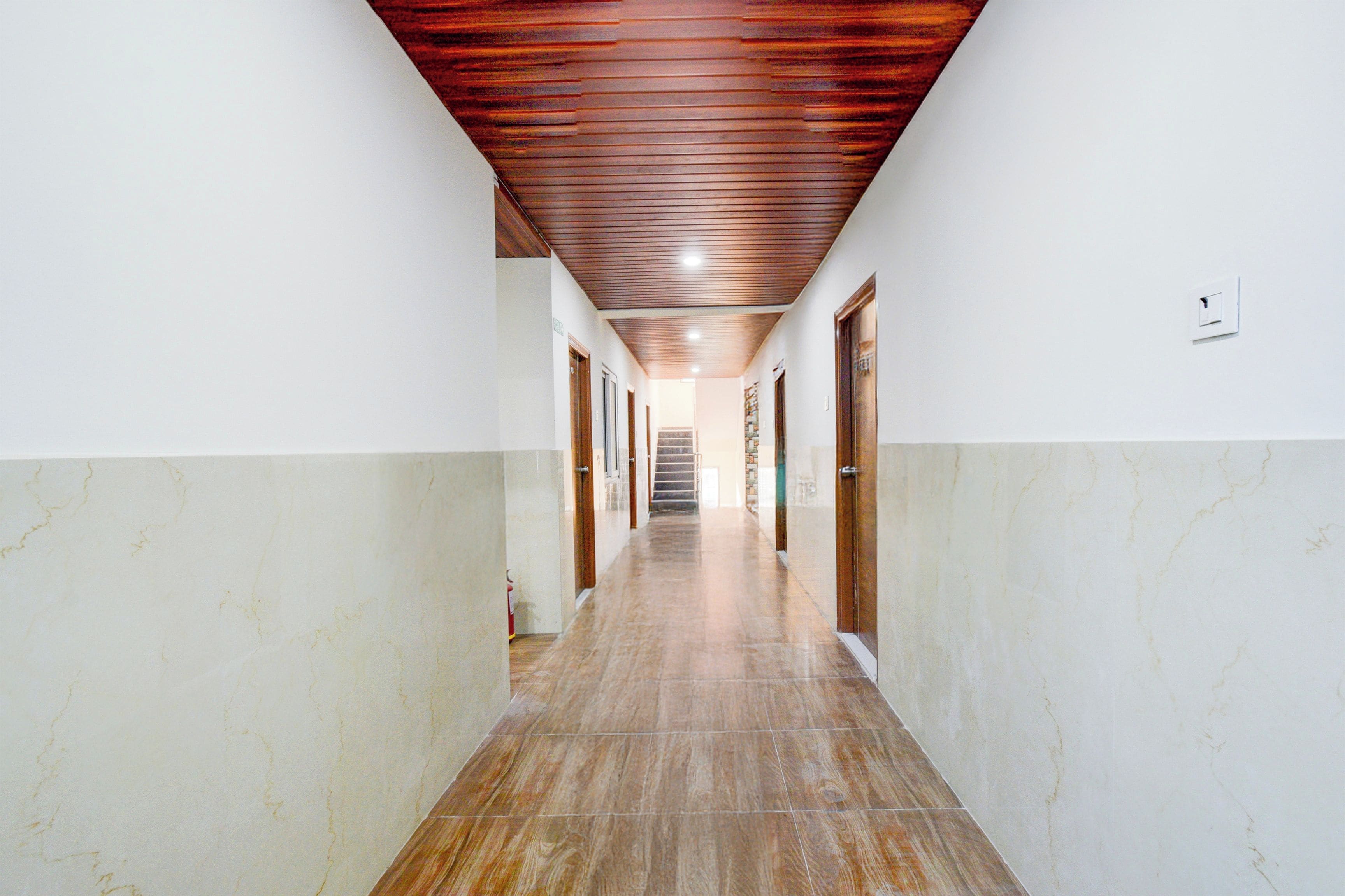 A long, narrow hallway with a wooden ceiling and marble walls.